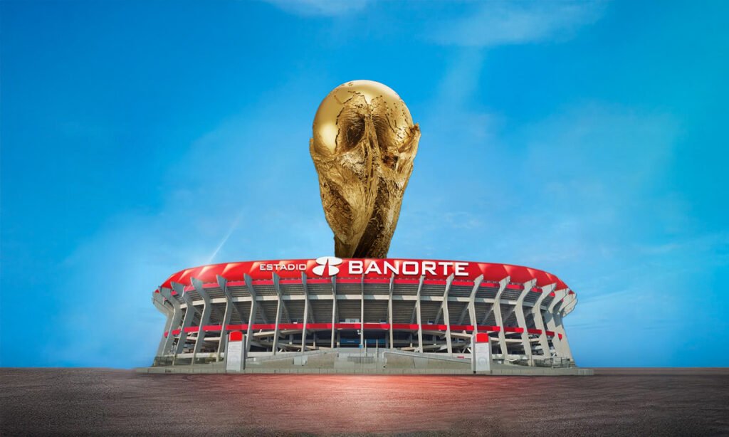Montaje fotográfico del Estadio Banorte en México con el Trofeo de la Copa Mundial de la FIFA emergiendo del centro, sobre un fondo de cielo azul claro.