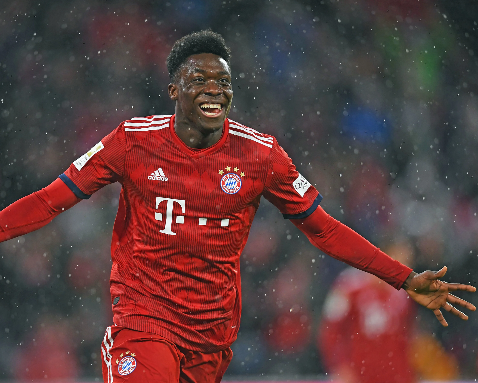 Alphonso Davies celebrando con el FC Bayern München bajo la lluvia durante un partido de la Bundesliga.
