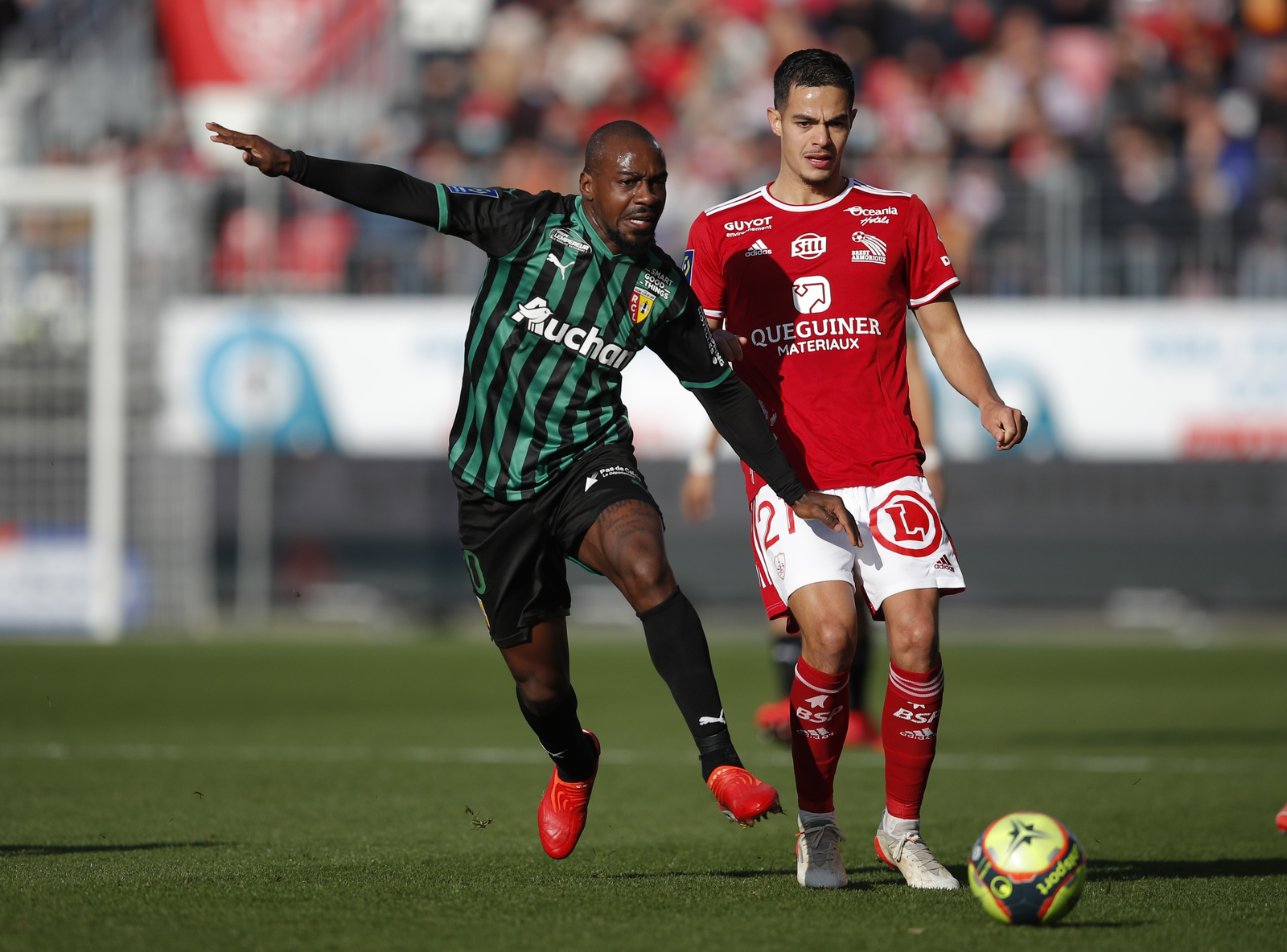 Gaël Kakuta del RC Lens protegiendo el balón ante la marca de un defensor del Stade Brestois en un partido de la Ligue 1.