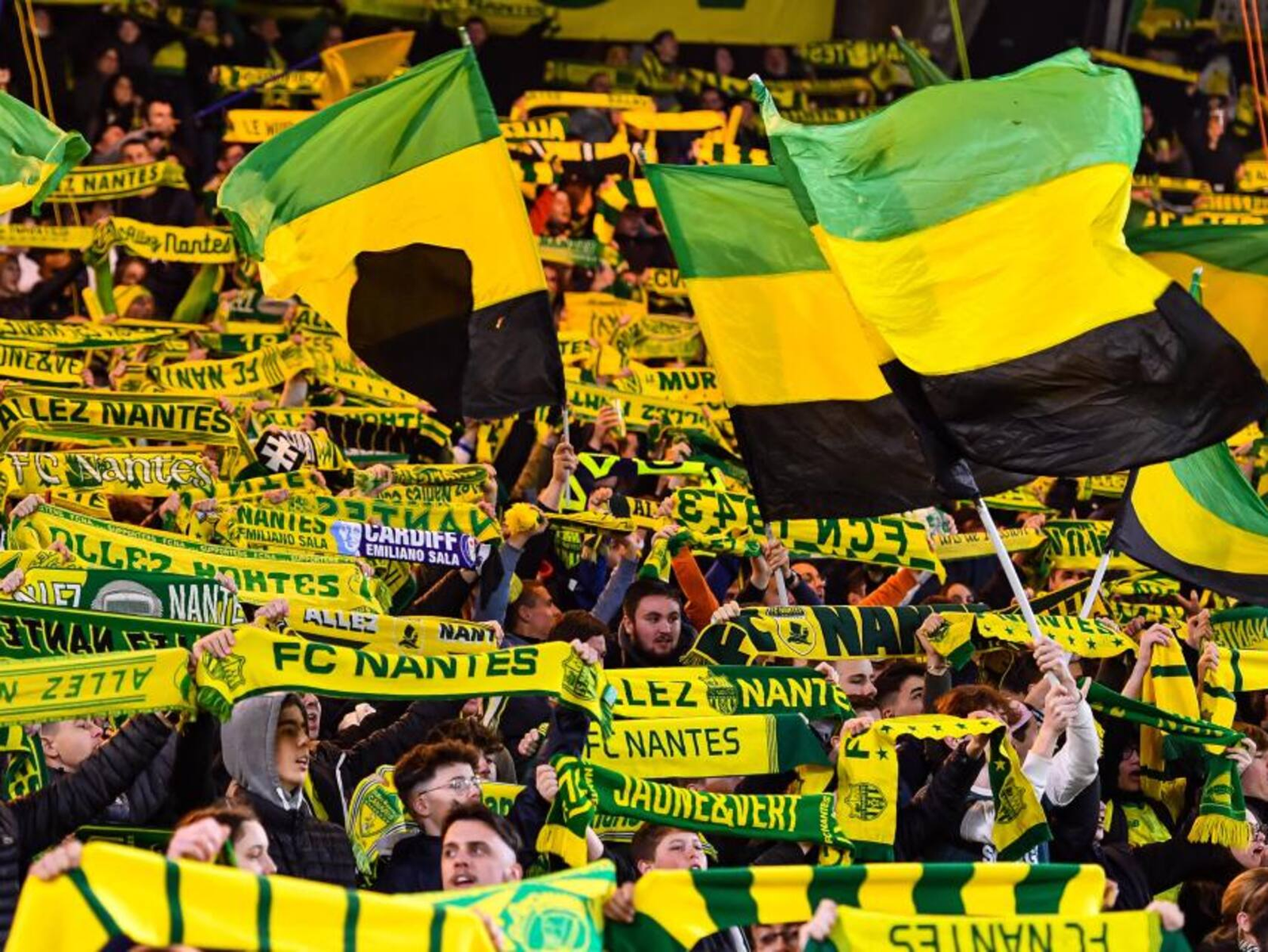 Aficionados del FC Nantes desplegando bufandas y banderas amarillas y verdes en las gradas del Estadio de la Beaujoire.