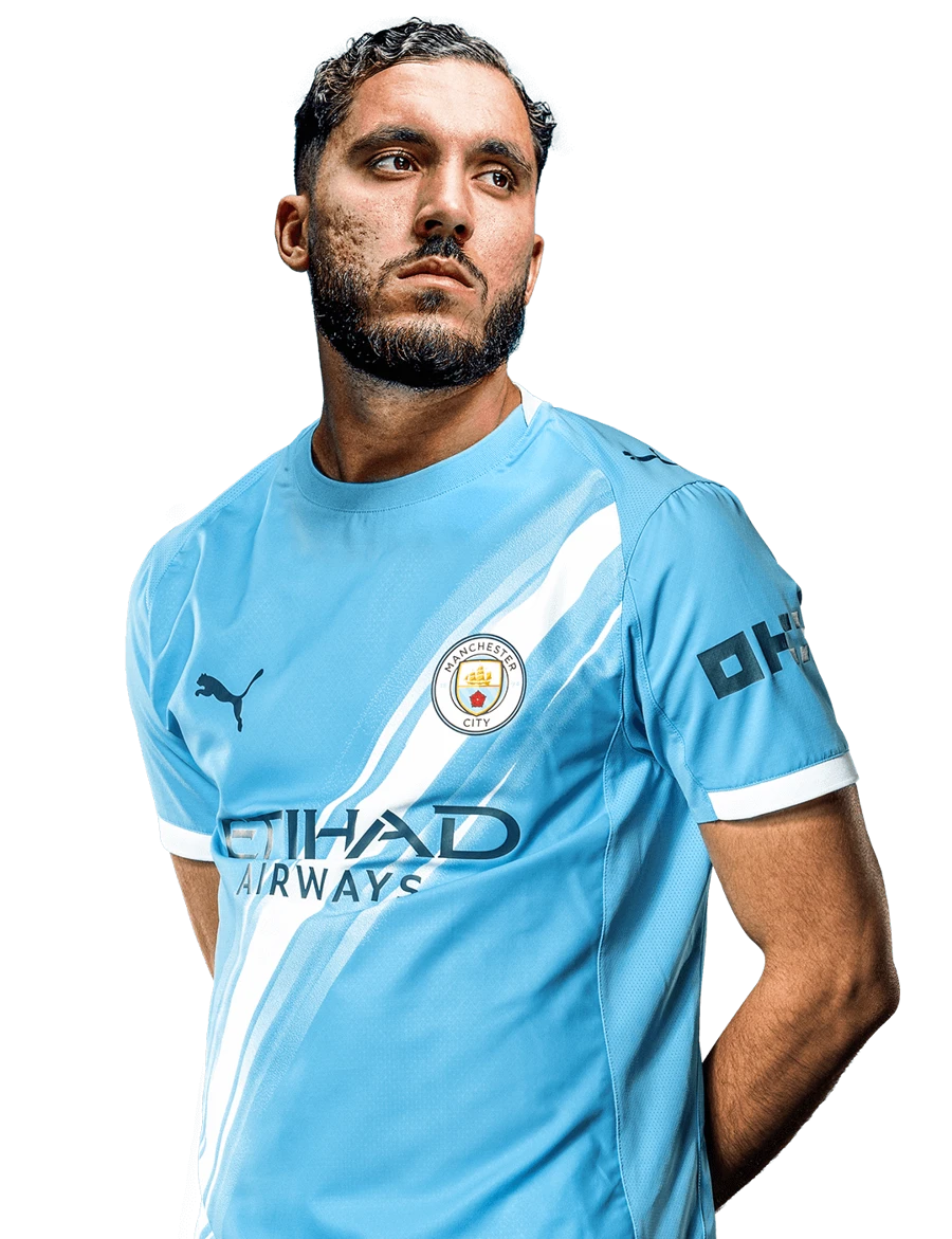 MANCHESTER CITY Retrato de primer plano del futbolista Rayan Cherki posando con la camiseta de local del Manchester City sobre un fondo negro sólido.