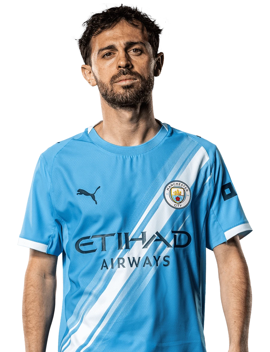 MANCHESTER CITY Retrato frontal del futbolista Bernardo Silva posando con la camiseta de local del Manchester City sobre un fondo negro sólido.
