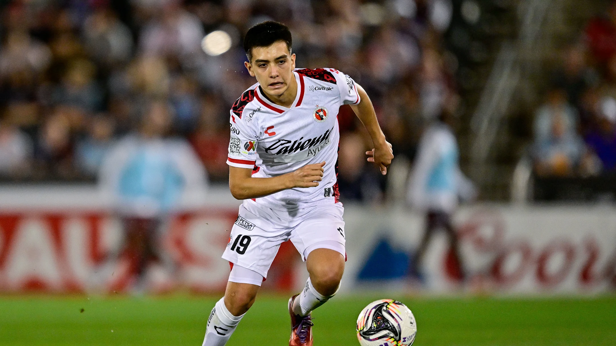 Gilberto Mora, centrocampista de Xolos de Tijuana, conduciendo el balón durante un partido de la Liga MX.