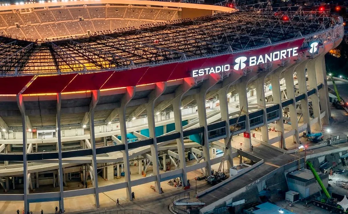 Vista exterior nocturna del Estadio Banorte en Ciudad de México, mostrando la estructura iluminada, el letrero principal y parte del techo metálico durante su fase de remodelación.